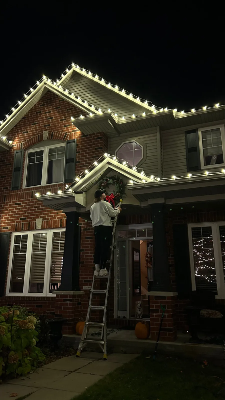 Holiday lighting along the roofline of a home photographed from the driveway