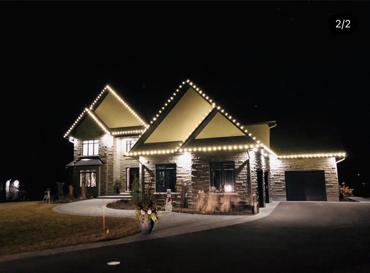 Holiday lighting outlining the roofline and entry of a residential home at night