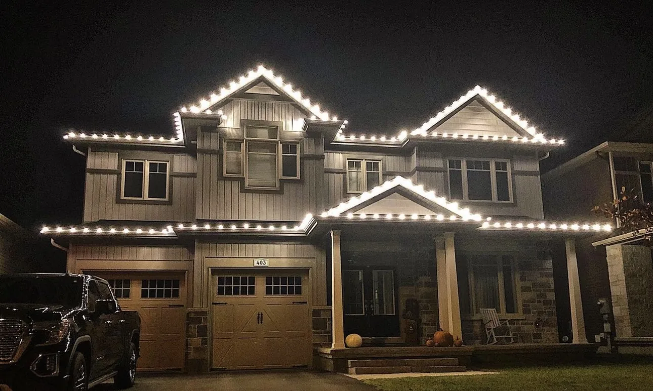 Two-story farmhouse with crisp warm white lighting along each roof peak