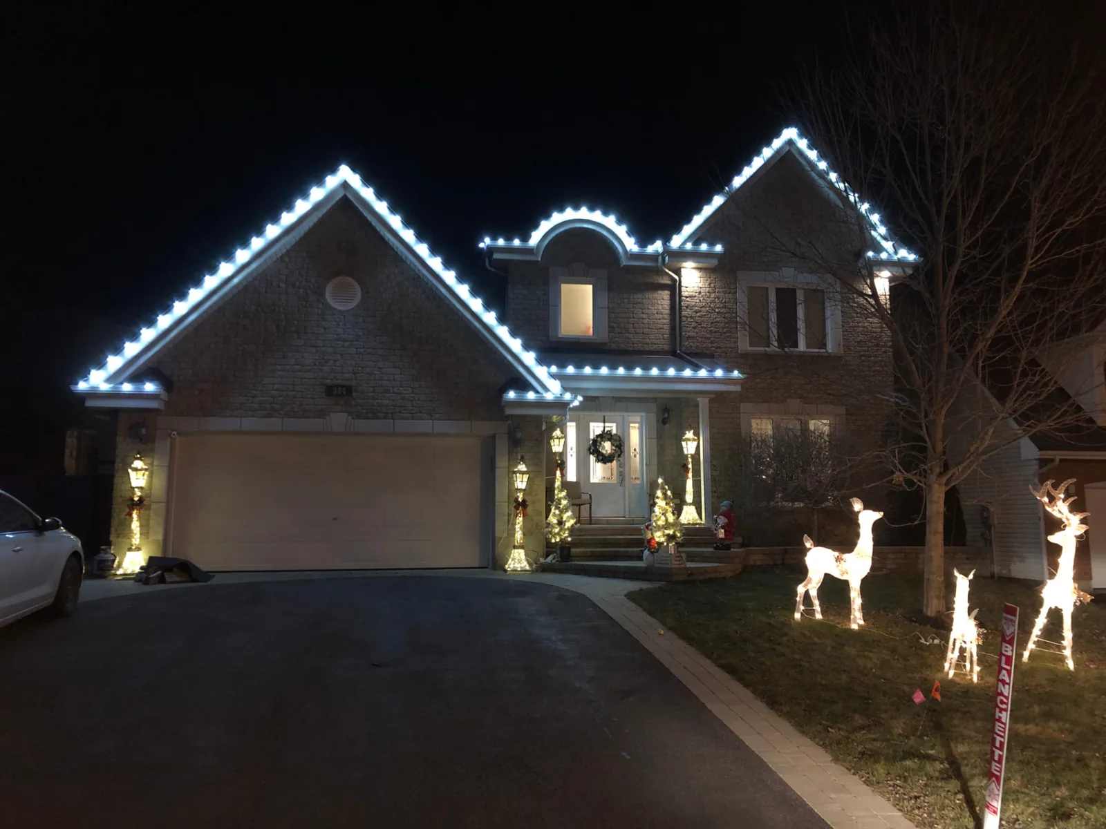 Evening photo of a home outlined with holiday lighting