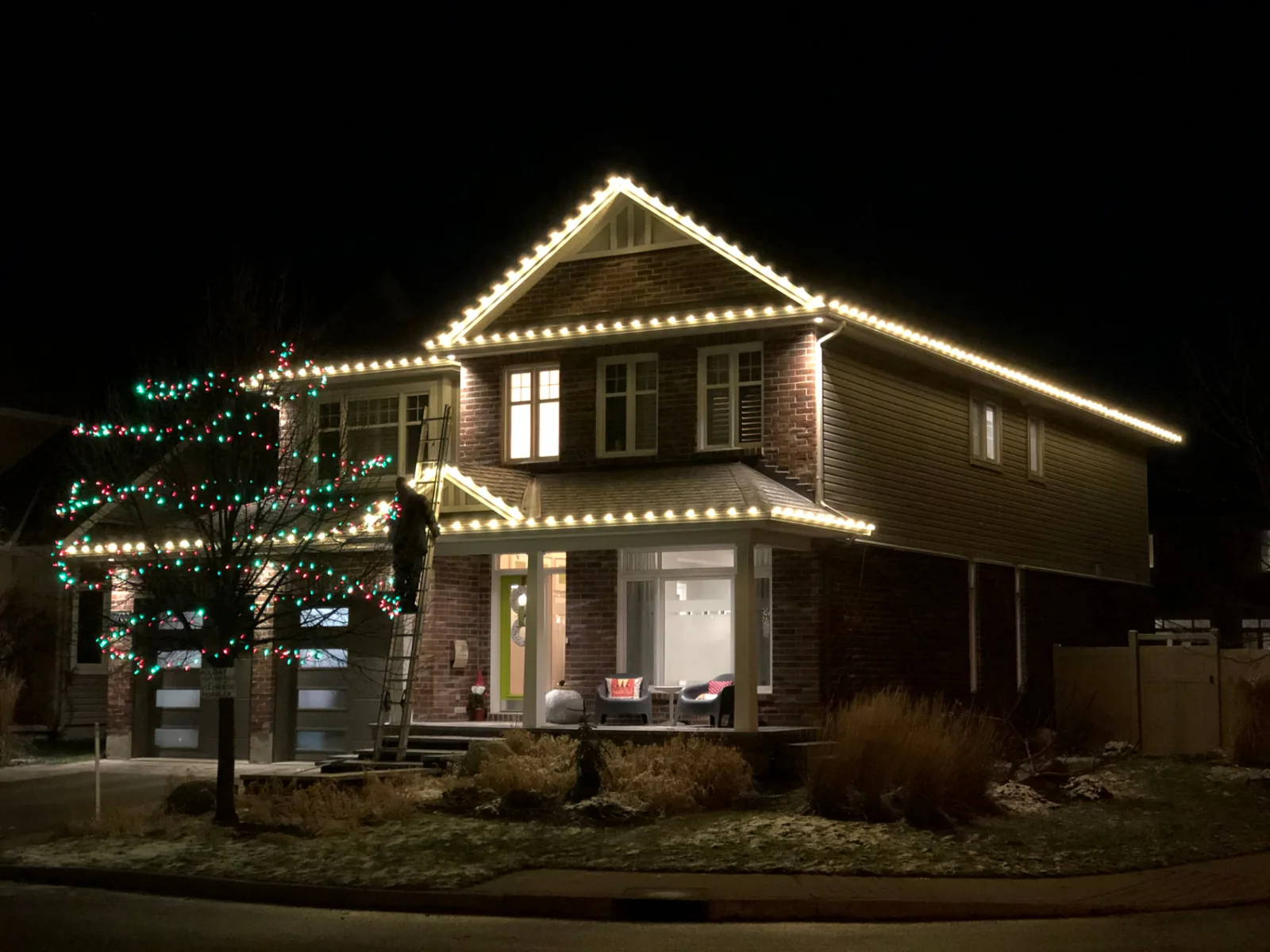 Home lit with holiday roofline lighting on a winter evening