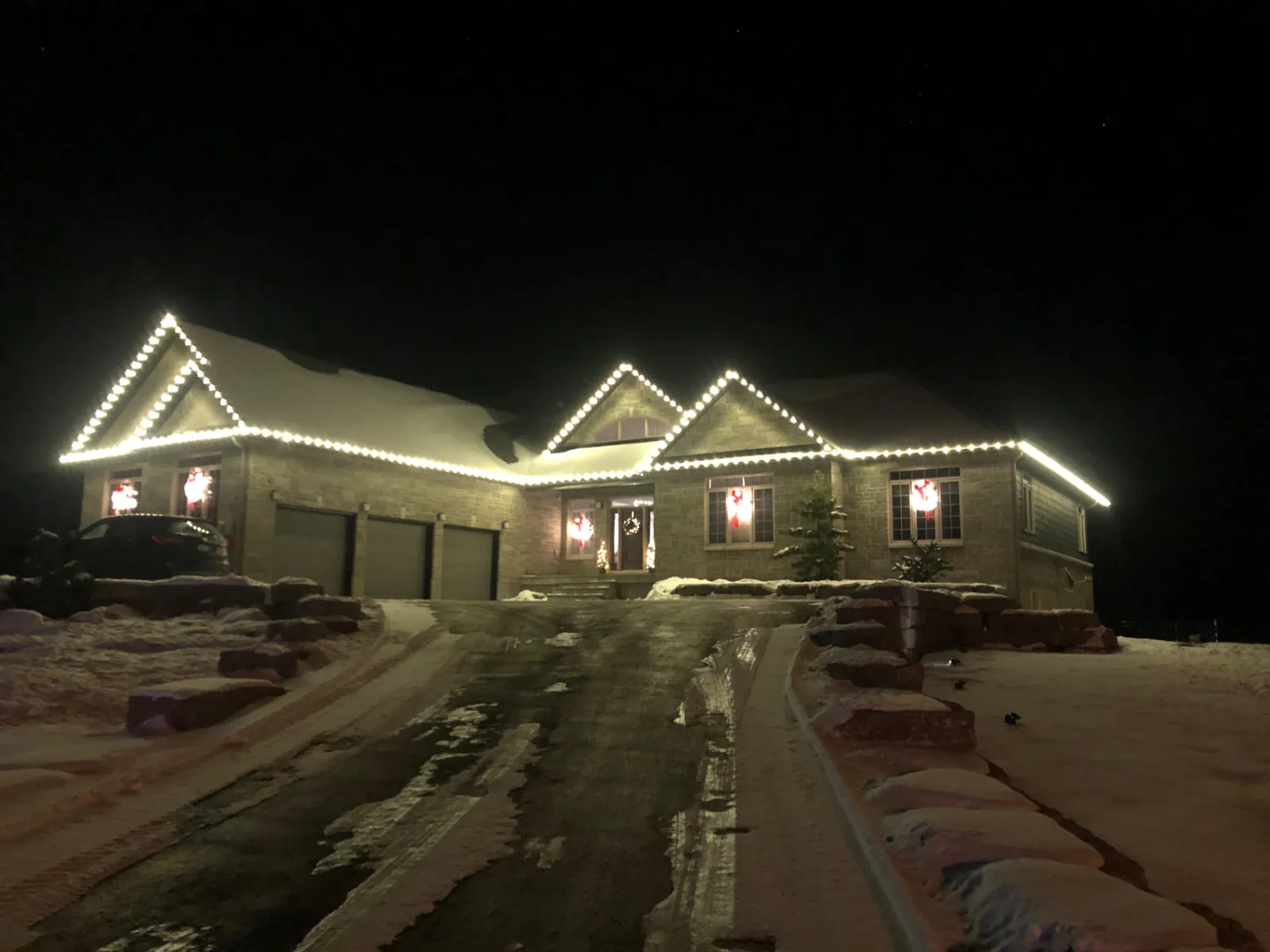Home with holiday lighting tracing the roof edges and garage